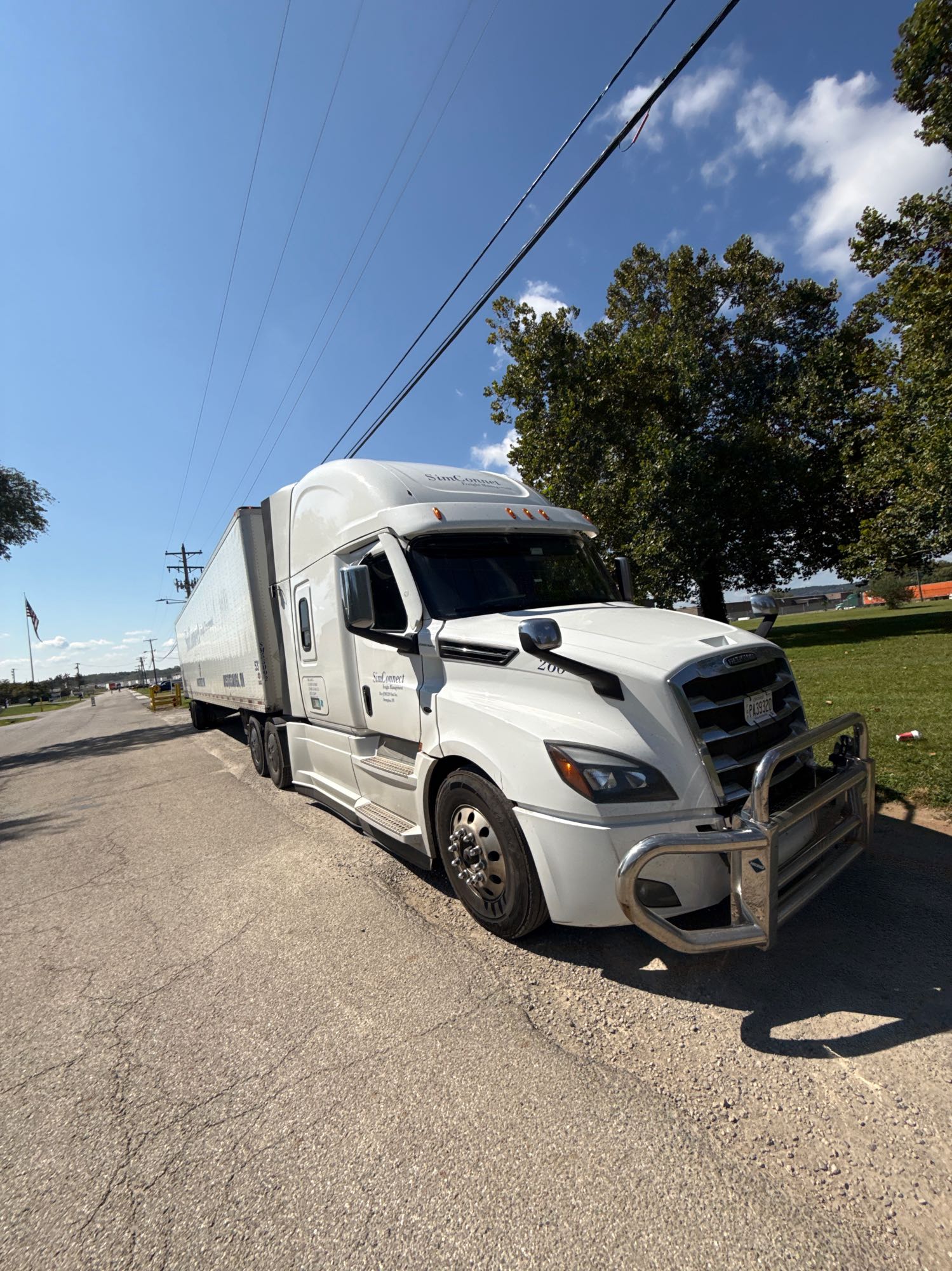 A white SimConnect tractor and trailer parked outdoors in daylight